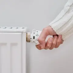 Mano ajustando el termostato de un radiador para saber como encender la calefacción.