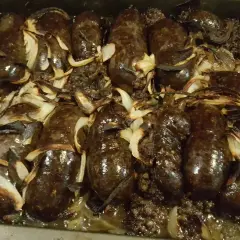 Kaszanka pieczona w piekarniku z cebulą, apetycznie przyrumieniona, gotowa do podania.