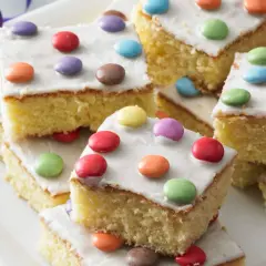 Bunte Smarties-Kuchenstücke auf einem Teller, ein leckeres fantakuchen rezept für Kindergeburtstage.