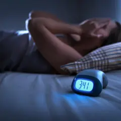 Persona en la cama, cubriéndose la cara, con un despertador marcando las 3:41. Parece que está teniendo una pesadilla, como si soñara que te persiguen para matarte.