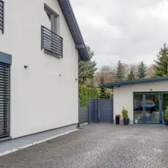 Nowoczesny dom w Dąbrowie Górniczej z podjazdem z kostki brukowej, garażem i zielenią.