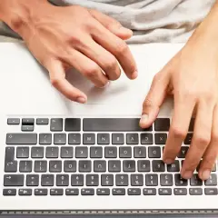 Dłonie na klawiaturze laptopa, jak odblokować klawiaturę w laptopie.