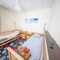 Pokój z dwoma łóżkami, szafkami nocnymi i kolorowym dywanem.