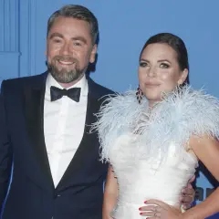 Mąż Oli Kwaśniewskiej, Piotr, w eleganckim smokingu u boku żony w białej sukni z piórami.