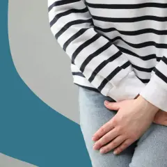 Femme tenant ses mains sur son bas-ventre, évoquant la gêne d'une fuite urinaire liée à la ménopause.