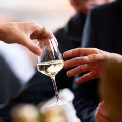 Des mains échangent un verre de vin blanc lors d'une dégustation à Angers.