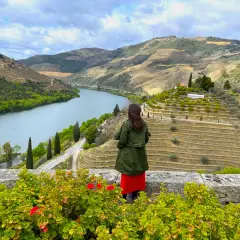 Mujer admira la impresionante **ruta del Duero**, con sus viñedos en terrazas y el río serpenteando entre colinas verdes.