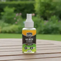Butelka sprayu "No Bite" z 30% DEET, najmocniejszy środek na komary i kleszcze, na drewnianym stole w ogrodzie.