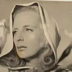 Portret Tamary Łempickiej w nakryciu głowy, z lokami opadającymi na ramiona.