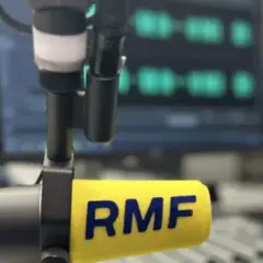 Mikrofon radiowy z logo RMF FM na tle ekranu z falami dźwiękowymi.