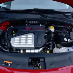 Silnik fiat bravo 1.4 t-jet w komorze pod maską. Widoczny akumulator, układ dolotowy i osłona silnika.