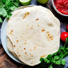 Frische Tortillas, perfekt für jedes Tortilla Rezept, mit Salsa, Tomaten und Koriander auf Holztisch.
