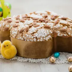 Colomba pasquale, un classico tra i dessert pasquali, decorata con mandorle e zuccherini, circondata da pulcini e uova di cioccolato.