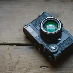 A Leica CL camera with a Nokton Classic lens rests on a weathered wooden surface, ready for a detailed review.