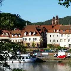 Idyllische Kulisse am Flussufer mit Fachwerkhäusern und Kirchturm. Vielleicht gibt es heute Veranstaltungen in Mosbach?