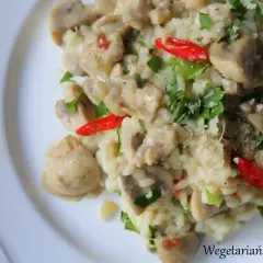 Kremowe risotto z pieczarkami, ozdobione natką pietruszki i ostrą papryczką. Idealne danie dla miłośników grzybów.