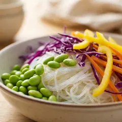 Schüssel mit Glasnudeln, Edamame, Rotkohl, Karotten und gelbem Paprika. Sind Glasnudeln gesund? Ja, sie sind eine leichte und nährstoffreiche Option.