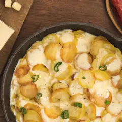 Plat gratiné de pommes de terre et fromage fondant, parfait pour une recette diots de Savoie. Accompagné de saucisses savoureuses.