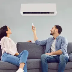 Pareja disfrutando del confort de su hogar con un aire acondicionado que ofrece un boost de aire fresco.