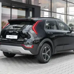 Czarny Kia Niro Hybrid stoi przed salonem. Elegancki tył auta z charakterystycznymi światłami i napisem "Niro Hybrid" przyciąga wzrok.