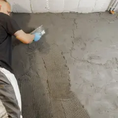 Arbeiter trägt Mörtel auf Kellerwand auf. Dies ist Teil der Arbeiten zum Keller ausschachten und abdichten, um Kosten zu sparen.