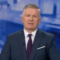 Mężczyzna w garniturze, prowadzący tvn wiadomości, z uwagą przekazuje informacje.