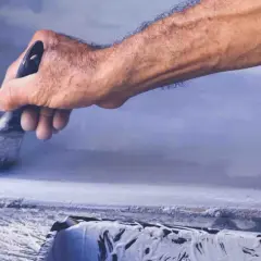 Mano che usa un pennello per pitturare cemento grezzo, proteggendo la parete ruvida.