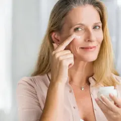 Frau trägt Vitamin A Kosmetik auf, um ihre Haut zu pflegen.