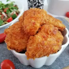 Chrupiące nuggetsy na zimno, idealne na szybką przekąskę. Obok świeża sałatka i pomidorki.