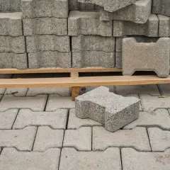 Stos kostki brukowej na palecie i pojedyncze kostki na ułożonej nawierzchni.