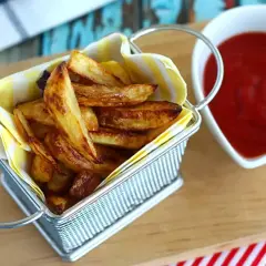 En korg med gyllene pommes frites, redo att doppas i ketchup. Perfekt för en mysig kväll.