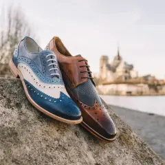 Eleganckie męskie buty derby, jeden w odcieniach niebieskiego i białego, drugi brązowy. Idealne na spacer po Paryżu.