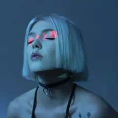Kobieta z neonowym makijażem oczu, w czarnym chokerze. Krotkie sa momenty, ulotne jak światło na powiekach.