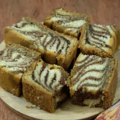 Kawałki ciasta zebra, z charakterystycznym wzorem przypominającym paski zebry, ułożone na drewnianej desce. To stary przepis na ciasto zebra, który wciąż zachwyca.