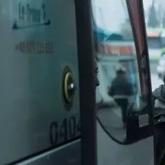 Młoda kobieta patrzy w lustro autobusu, marząc, by jak najdalej stad.