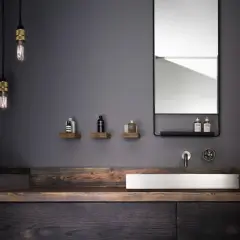 Modernes schwarzes Bad mit Holz. Ein Waschbecken aus Stein auf einem dunklen Holzunterschrank, flankiert von rustikalen Holzregalen mit Pflegeprodukten.