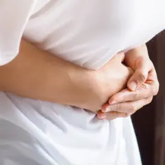 Osoba trzyma się za brzuch, odczuwając ostry ból w lewym boku.
