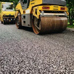 Walec drogowy ugniata świeżo położony asfalt na podjeździe.