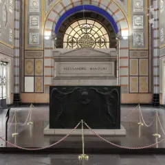 La tomba di Manzoni, imponente monumento con bassorilievi di angeli e ritratto, è protetta da cordoni dorati.