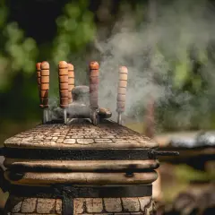 Dym unosi się z glinianego pieca tandoori, gdzie przygotowywane są aromatyczne potrawy.