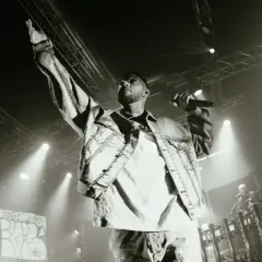 Emis Killa sul palco, con la mano alzata e il microfono in pugno, interpreta i suoi testi, parole di ghiaccio che riscaldano la folla.