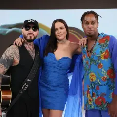 Trzech członków Blue Café w niebieskich strojach. Jeden z nich trzyma gitarę.