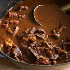 Un plat mijoté de carbonade flamande dans une cocotte en fonte, avec des morceaux de bœuf tendres et une sauce brune onctueuse.