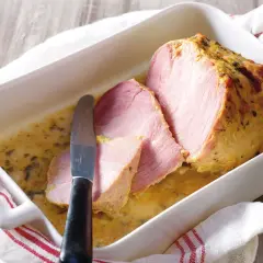 Palette à la diable, tranchée et servie dans un plat blanc avec une sauce dorée. Un couteau est posé sur la viande.