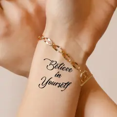 Dłoń z tatuażem "Believe in Yourself" i złotą bransoletką.