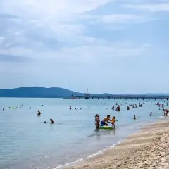 Plaża w Burgas, mnóstwo ludzi kąpiących się i opalających. Długie molo, góry w tle. Burgas czy warto? Zdecydowanie tak!
