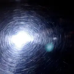 Efekt wiru po polerowaniu lakieru po malowaniu sprayem. Jasne światło odbija się od powierzchni, tworząc spiralne refleksy.