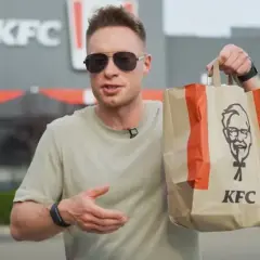 Mężczyzna trzyma torbę z KFC, zastanawiając się nad kalorycznością frytek.