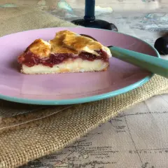 Porción de pastel vasco con relleno de crema y frutos rojos, servida en plato rosa.