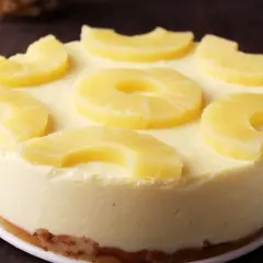 Tarta de piña cremosa, decorada con rodajas y trozos de piña fresca. Un postre tropical irresistible.